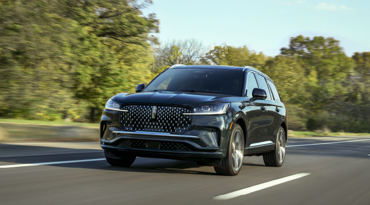 A 2025 Lincoln Black Label Aviator® SUV is being driven down a road lined with trees. | Thornhill Lincoln in Chapmanville WV