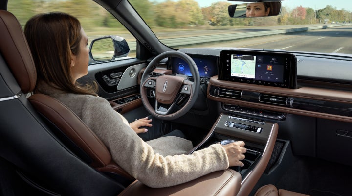 A 2026 Lincoln Aviator® SUV is being driven hands-free on a highway near a forest | Thornhill Lincoln in Chapmanville WV
