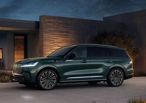 A green 2027 Lincoln Aviator® SUV is parked outside a contemporary home. | Thornhill Lincoln in Chapmanville WV