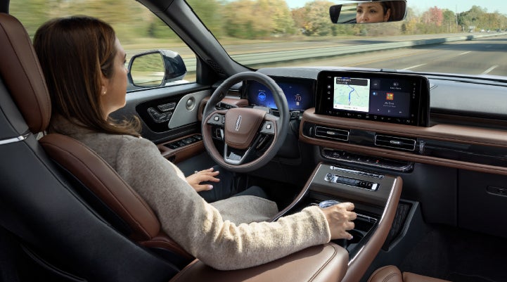 A 2027 Lincoln Aviator® SUV is being driven hands-free on a highway lined with trees. | Thornhill Lincoln in Chapmanville WV