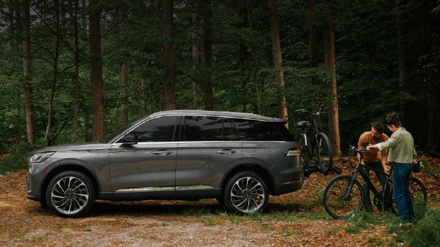 A father and son load e-bikes on a bike rack attached to a 2027 Lincoln Aviator® SUV. | Thornhill Lincoln in Chapmanville WV