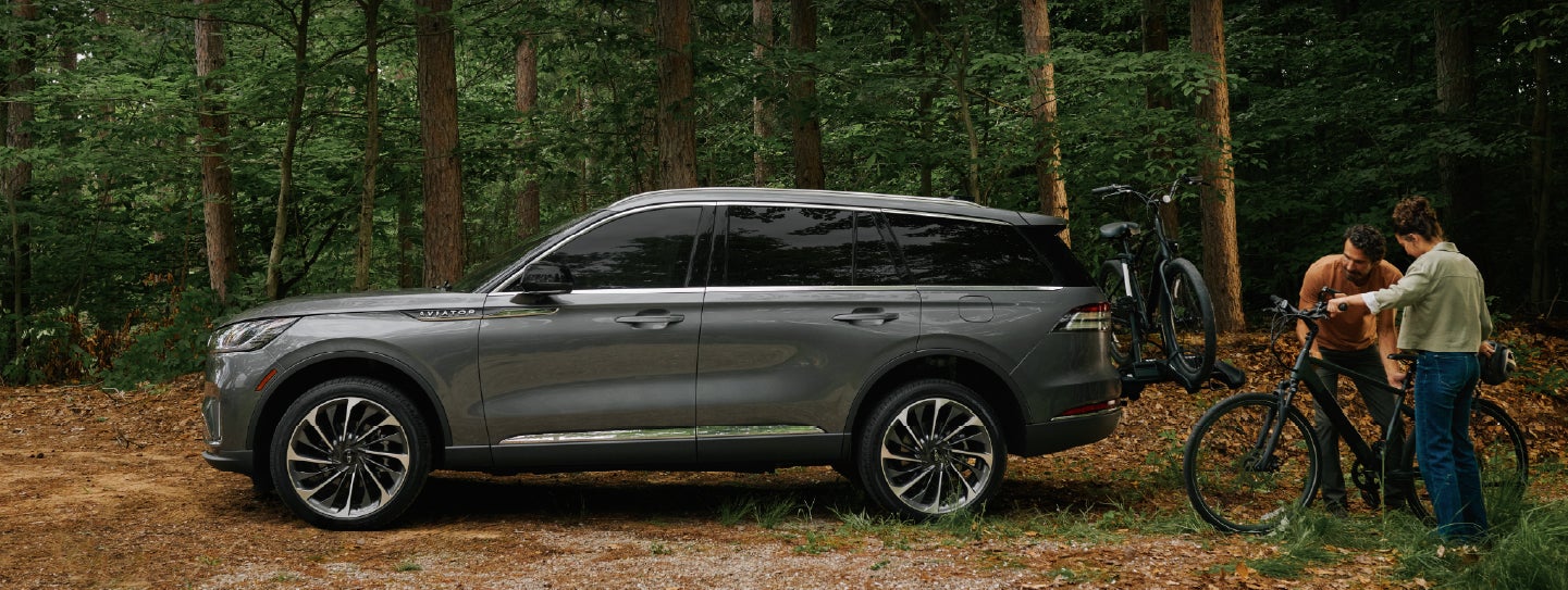 A father and son load e-bikes on a bike rack attached to a 2027 Lincoln Aviator® SUV. | Thornhill Lincoln in Chapmanville WV